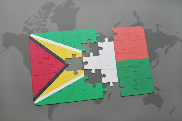 Puzzle mit der Nationalflagge von Guyana und Madagaskar auf einer Weltkarte — Stockfoto