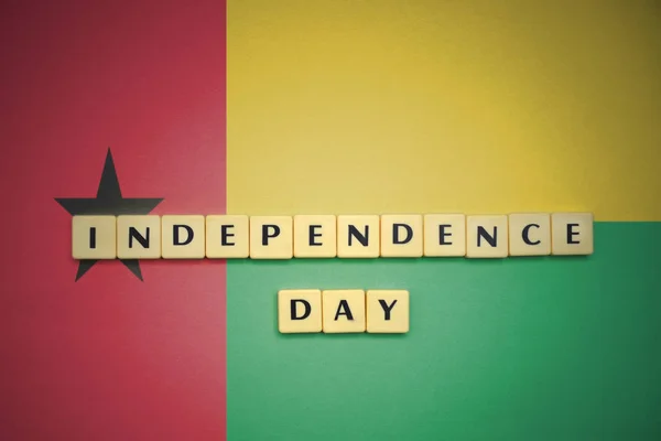 Cartas com o dia de independência de texto na bandeira nacional de guiné bissau . — Fotografia de Stock