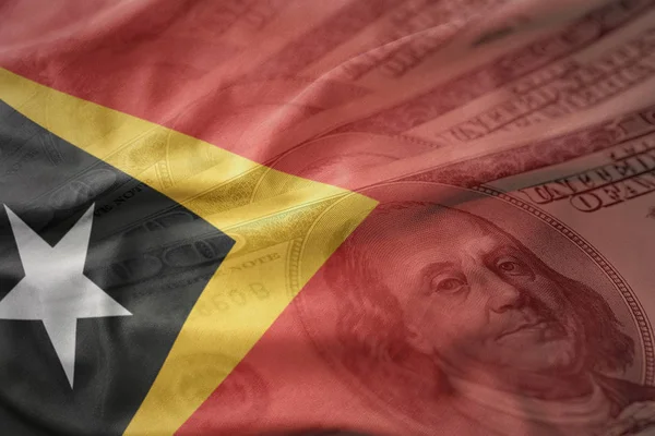 Coloré agitant drapeau national du Timor oriental sur un fond d'argent dollar américain. concept de financement — Photo
