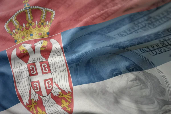 Πολύχρωμο κυματίζει η εθνική σημαία της Σερβίας σε αμερικανικό δολάριο χρήματα φόντο. έννοια των οικονομικών — Φωτογραφία Αρχείου