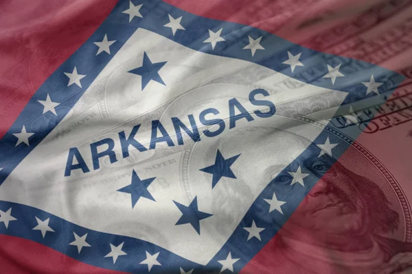 Bandera ondeando colorido del estado de Arkansas en un fondo de dinero del dólar americano. concepto de financiación — Foto de Stock