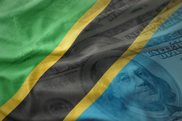 Coloré agitant drapeau national de la tanzanie sur un fond d'argent dollar américain. concept de financement — Photo