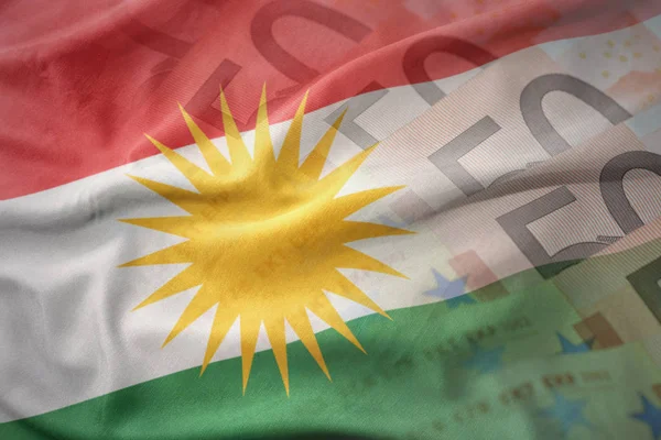 Bandiera nazionale sventolante colorata di kurdistan su uno sfondo di banconote in euro. concetto di finanziamento — Foto Stock