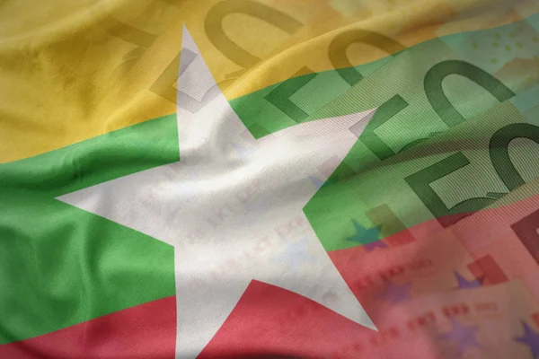 Colorido ondeando la bandera nacional de myanmar en un fondo de billetes de dinero en euros. concepto de financiación — Foto de Stock