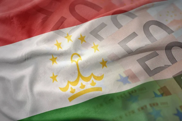 Kleurrijke wapperende vlag van Tadzjikistan op een euro geld bankbiljetten achtergrond. Financiën concept — Stockfoto