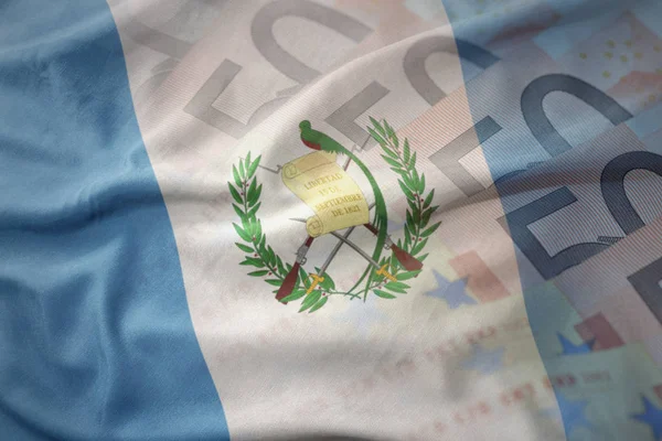 Barevné mávat státní vlajka Guatemaly na pozadí bankovky eura peníze. finanční koncept — Stock fotografie