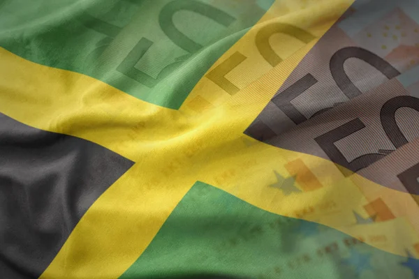 Colorido ondeando la bandera nacional de jamaica sobre un fondo de billetes de dinero en euros. concepto de financiación — Foto de Stock