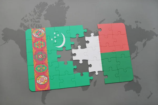 Puzzle con la bandiera nazionale del turkmenistan e madagvania su una mappa del mondo — Foto Stock