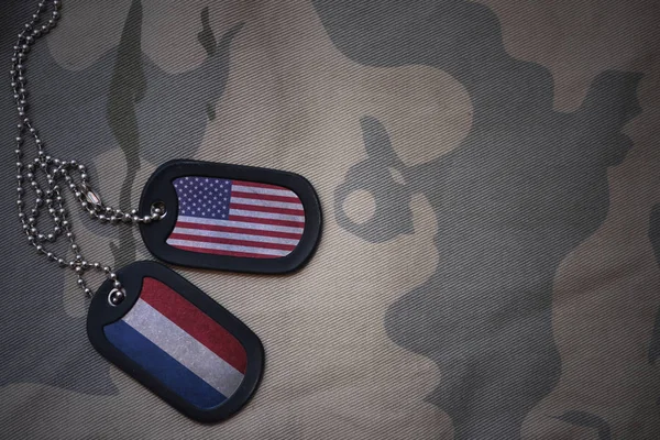 Ejército en blanco, etiqueta de perro con la bandera de los estados unidos de América y los Países Bajos en el fondo de textura caqui. concepto militar — Foto de Stock