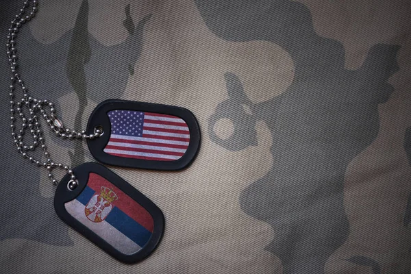 Hær blank, hund tag med flag af USA og serbien på khaki tekstur baggrund. militært koncept - Stock-foto
