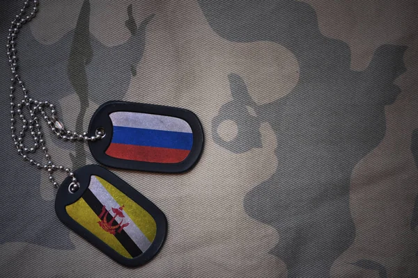 Esercito bianco, dog tag con bandiera di Russia e brunei sullo sfondo texture kaki. concetto militare — Foto Stock