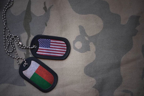 Армія пуста, собача мітка з прапором об'єднаних держав америки і мадагаскару на тлі текстури хакі. військова концепція — стокове фото