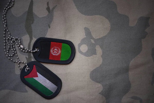 Army blank, dog tag with flag of palestine and afghanistan on the khaki texture background. military concept — Stock Photo, Image