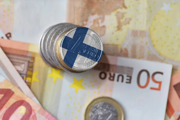 Euro-Münze mit finnischer Nationalflagge auf dem Hintergrund der Euro-Banknoten. — Stockfoto