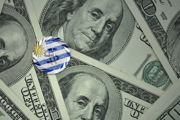 Монета с долларовым знаком с национальным флагом Уругвая на фоне банкнот с долларом — стоковое фото