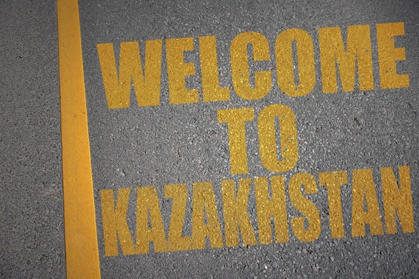 Estrada de asfalto com texto bem-vindo ao Cazaquistão perto da linha amarela . — Fotografia de Stock