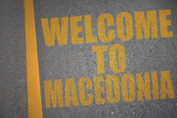 Strada asfaltata con testo benvenuto in macedonia vicino alla linea gialla . — Foto Stock