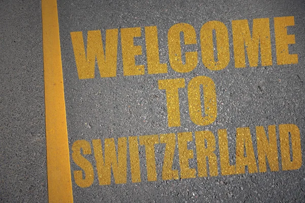 Estrada de asfalto com texto bem-vindo à Suíça perto da linha amarela . — Fotografia de Stock