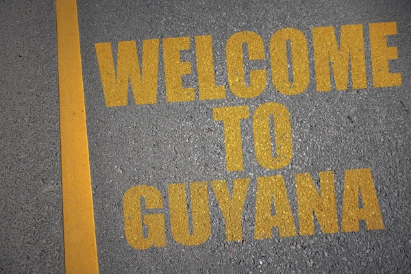 Asfaltweg met de tekst Welkom naar guyana in de buurt van gele lijn. — Stockfoto