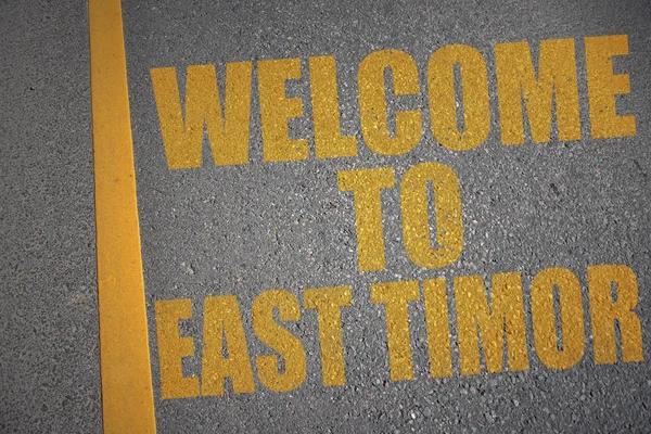 Strada asfaltata con testo benvenuto a timor est vicino alla linea gialla . — Foto Stock