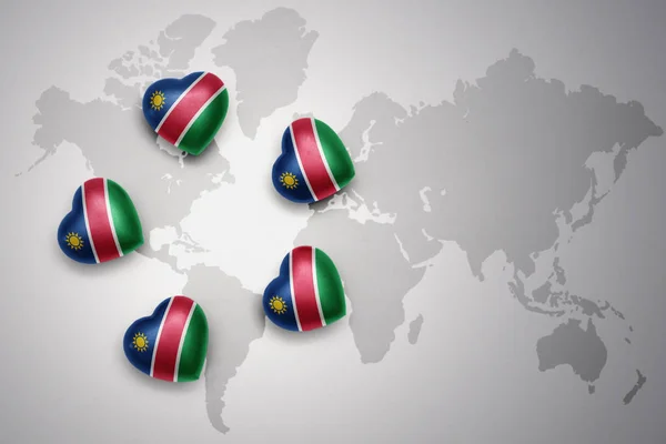 Fünf Herzen mit namibischer Nationalflagge auf dem Hintergrund einer Weltkarte — Stockfoto