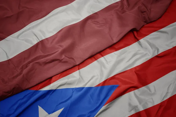 Хвилястий барвистий прапор Пуерто-Рико і національний прапор Латвії . — стокове фото
