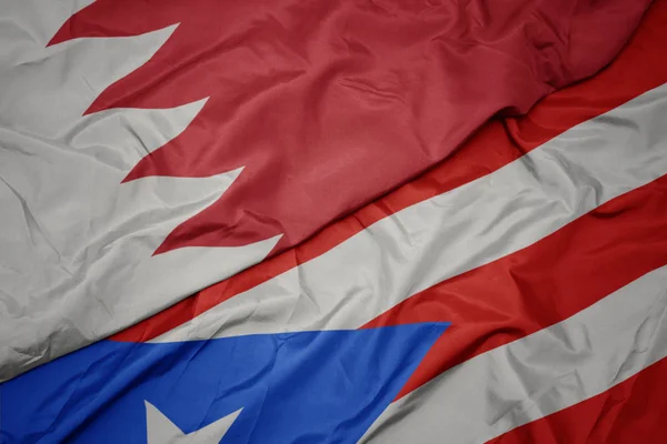 waving colorful flag of puerto rico and national flag of bahrain.