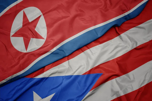 Schwenken bunte Flagge Puerto Ricos und Nationalflagge Nordkoreas. — Stockfoto