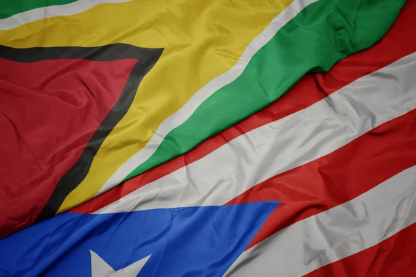 Machanie barwną flagą puerto rico i flagą narodową Gujany. — Zdjęcie stockowe