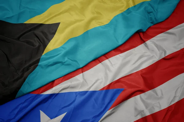 Agitant drapeau coloré de Porto rico et drapeau national des bahamas . — Photo