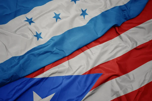 Ondeando colorida bandera de puerto rico y bandera nacional de honduras . — Foto de Stock