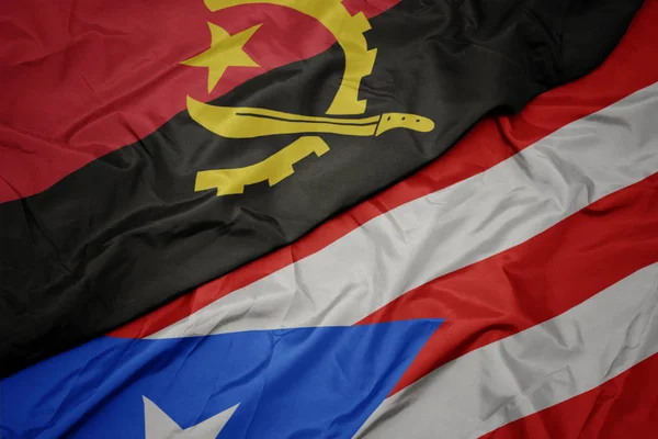 Waving colorful flag of puerto rico and national flag of angola. — Stockfoto