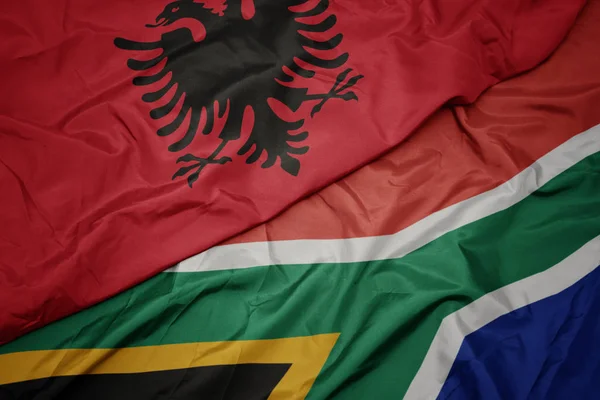 waving colorful flag of south africa and national flag of albania.