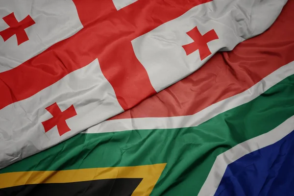 Acenando bandeira colorida da áfrica do sul e bandeira nacional da geórgia . — Fotografia de Stock