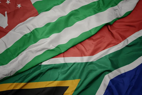 Acenando bandeira colorida da África do Sul e bandeira nacional da abcásia . — Fotografia de Stock