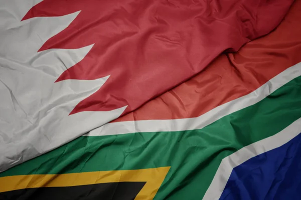 waving colorful flag of south africa and national flag of bahrain.