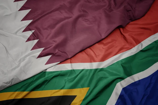 Mávání barevnou vlajkou Jižní Afriky a národní vlajkou Kataru. — Stock fotografie