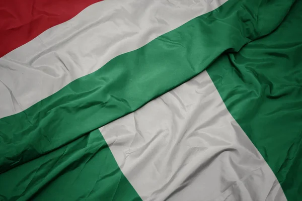 Lengető színes zászló Nigéria és a nemzeti zászló a magyar. — Stock Fotó