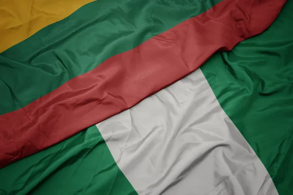 Ondeando colorida bandera de nigeria y bandera nacional de lithuania . — Foto de Stock
