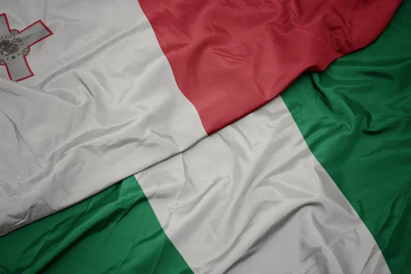 Waving colorful flag of nigeria and national flag of malta. — Stock Photo, Image