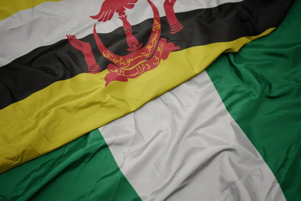 Agitant drapeau coloré de nigeria et drapeau national de brunei . — Photo