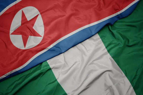 Sventolando bandiera colorata della Nigeria e bandiera nazionale della Corea del Nord . — Foto Stock