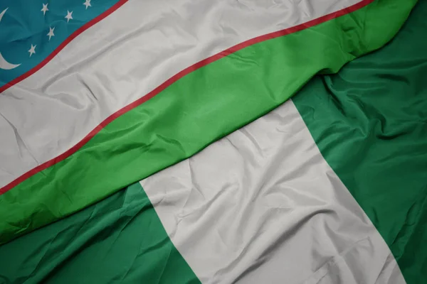 Ondeando colorida bandera de Nigeria y bandera nacional de Uzbekistán . —  Fotos de Stock