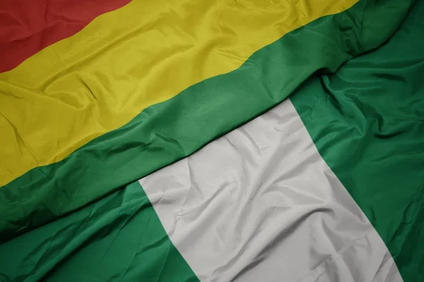 Ondeando colorida bandera de Nigeria y bandera nacional de Bolivia . — Foto de Stock