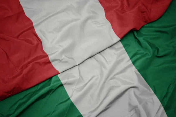 Nijerya 'nın renkli bayrağı ve Peru' nun ulusal bayrağı sallanıyor.. — Stok fotoğraf