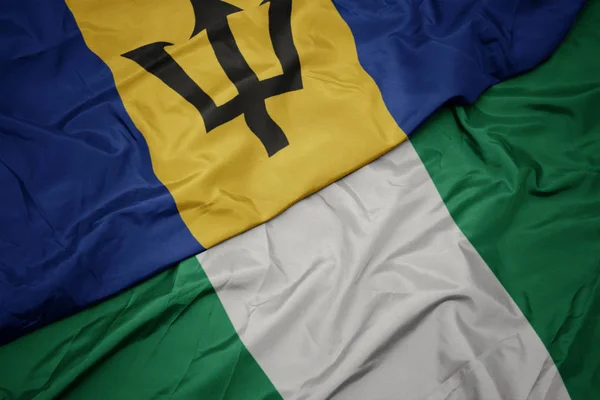 Machanie barwną flagą Nigerii i flagą narodową Barbadosu. — Zdjęcie stockowe