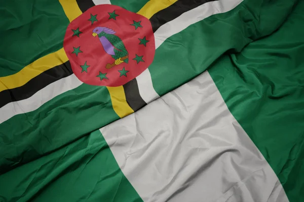 Agitant drapeau coloré du Nigéria et drapeau national de la Dominique . — Photo