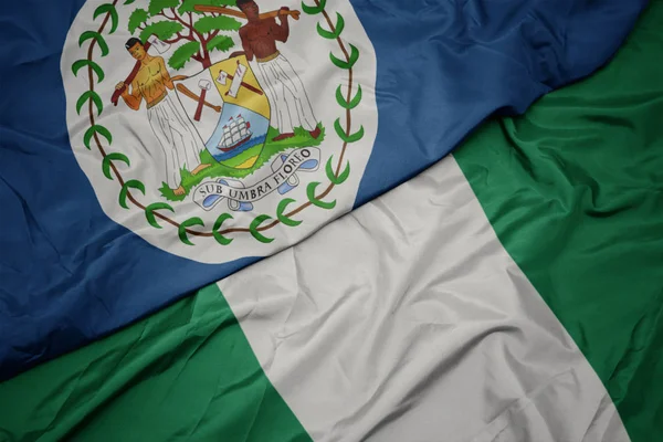 Ondeando colorida bandera de nigeria y bandera nacional de Belice . — Foto de Stock