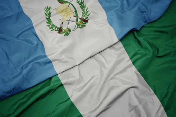 Mávání barevnou vlajkou Nigérie a národní vlajkou Guatemaly. — Stock fotografie
