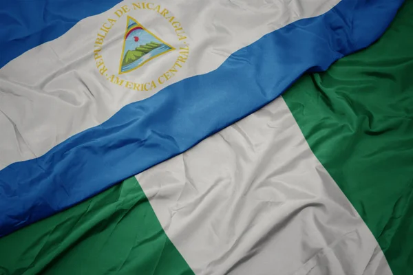 waving colorful flag of nigeria and national flag of nicaragua.